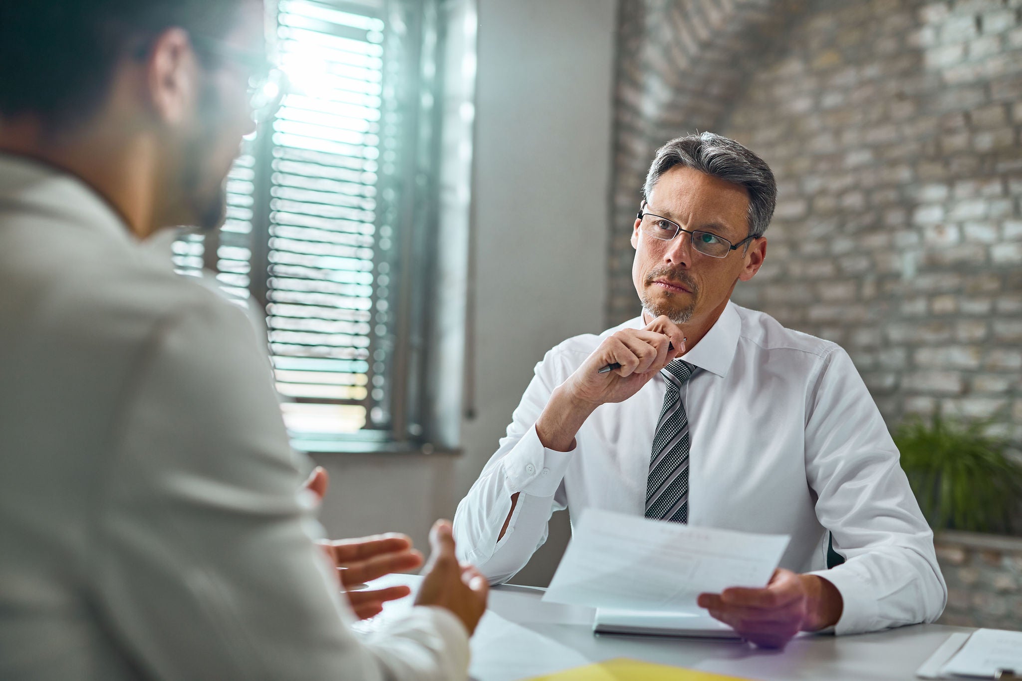 Mid adult businessman listening to a candidate during job interview in the office.