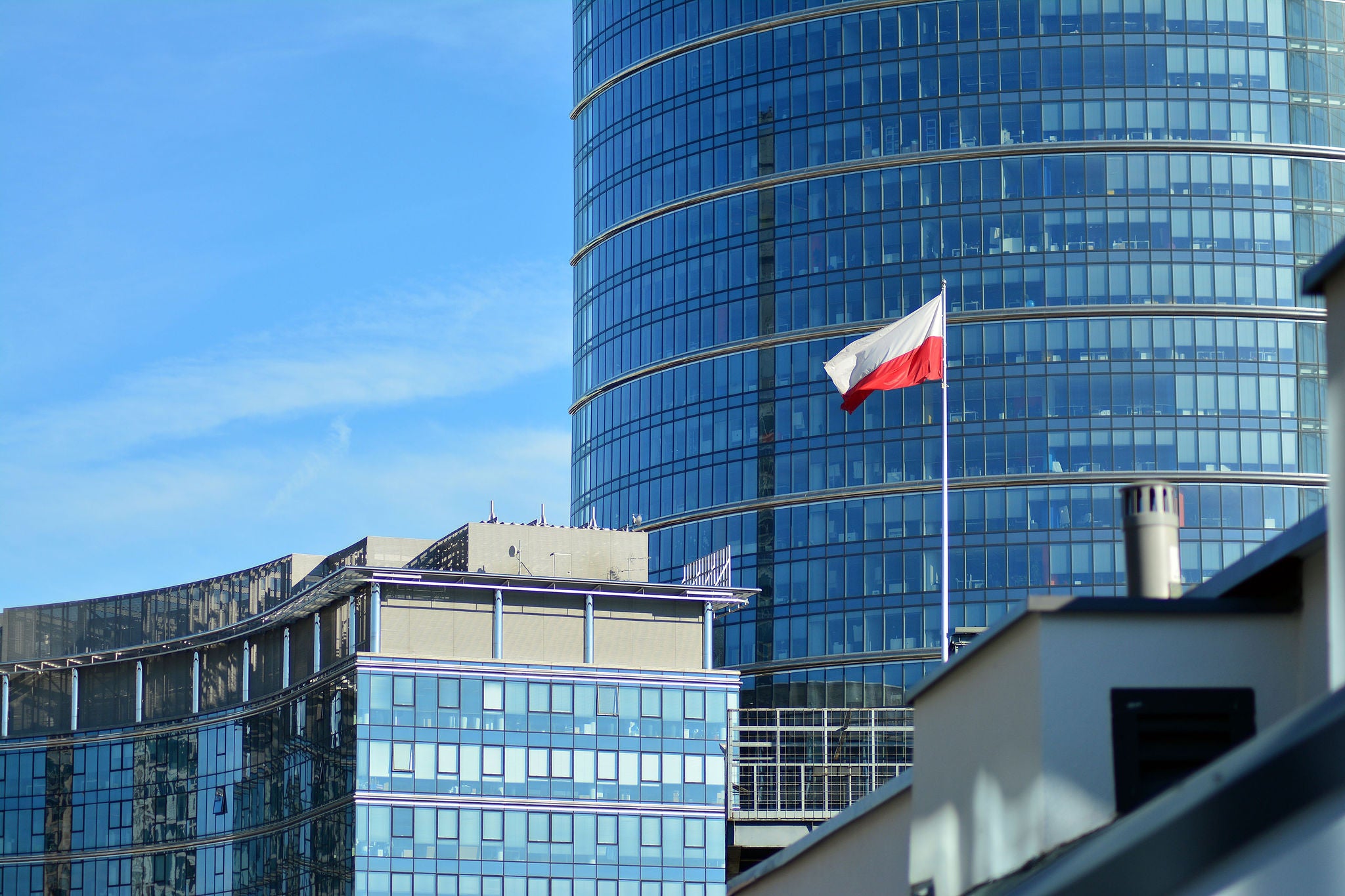  Polish flag on a pole waving, modern office building background