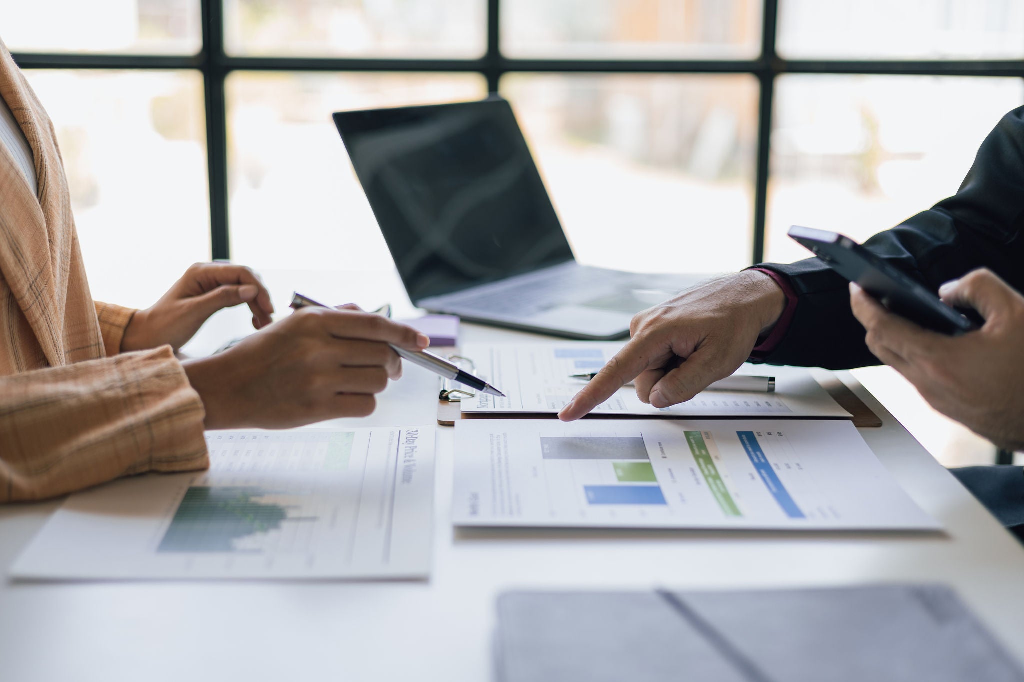 Meeting with a financial advisor and auditor are analyzing the financial figures in the business report. 