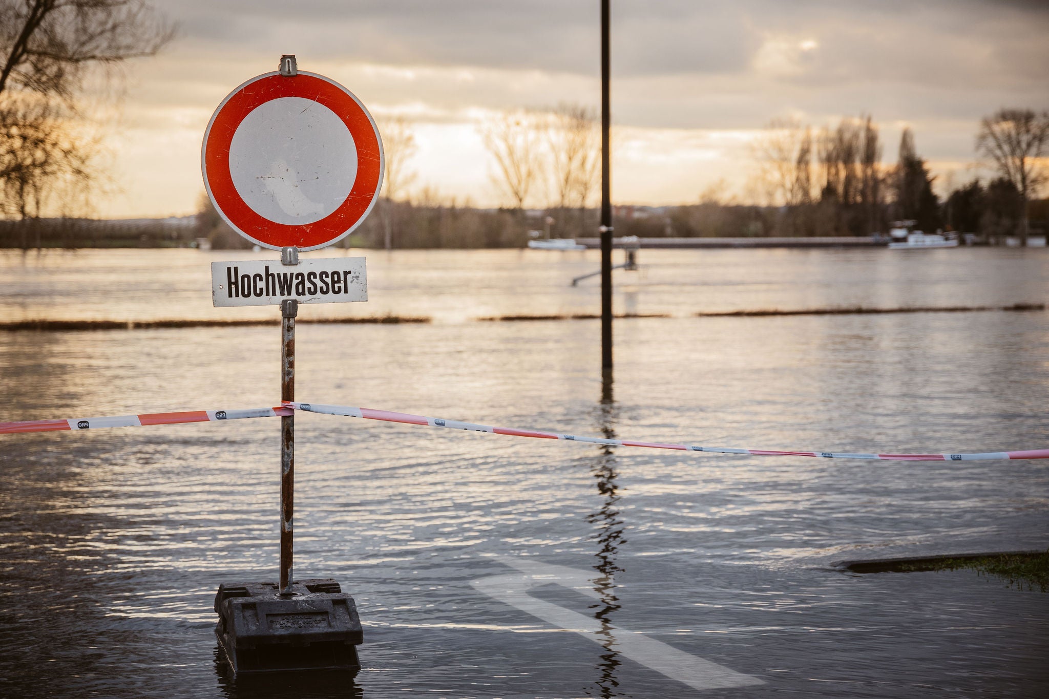 Schild Hochwasser vor überfluteter Straße