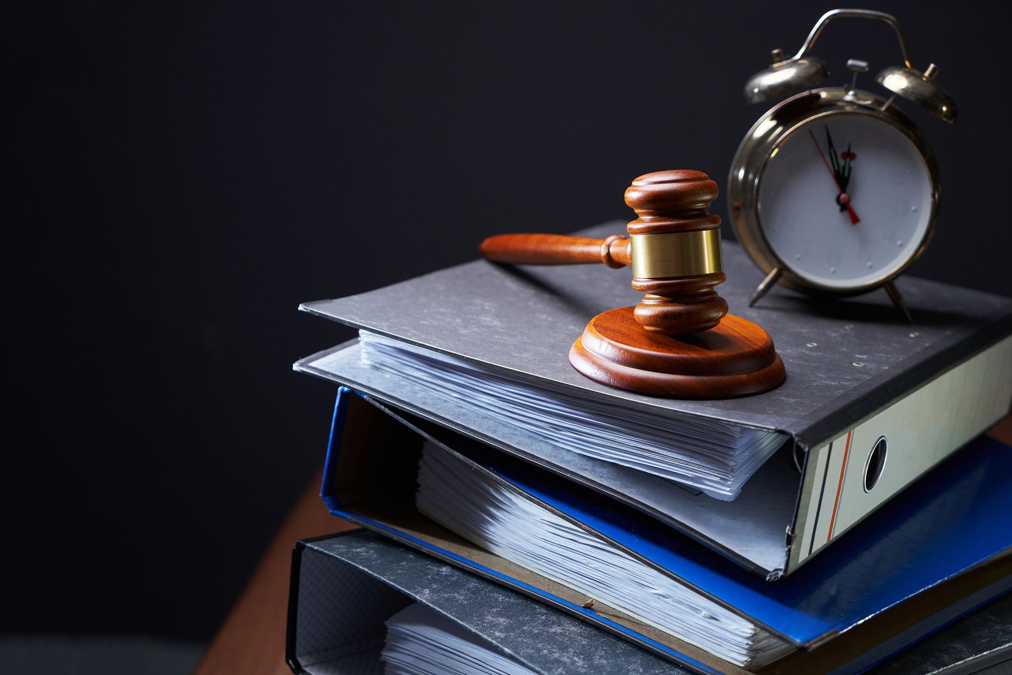 close-up of  gavel with stack of files and vintage alarm clock on table