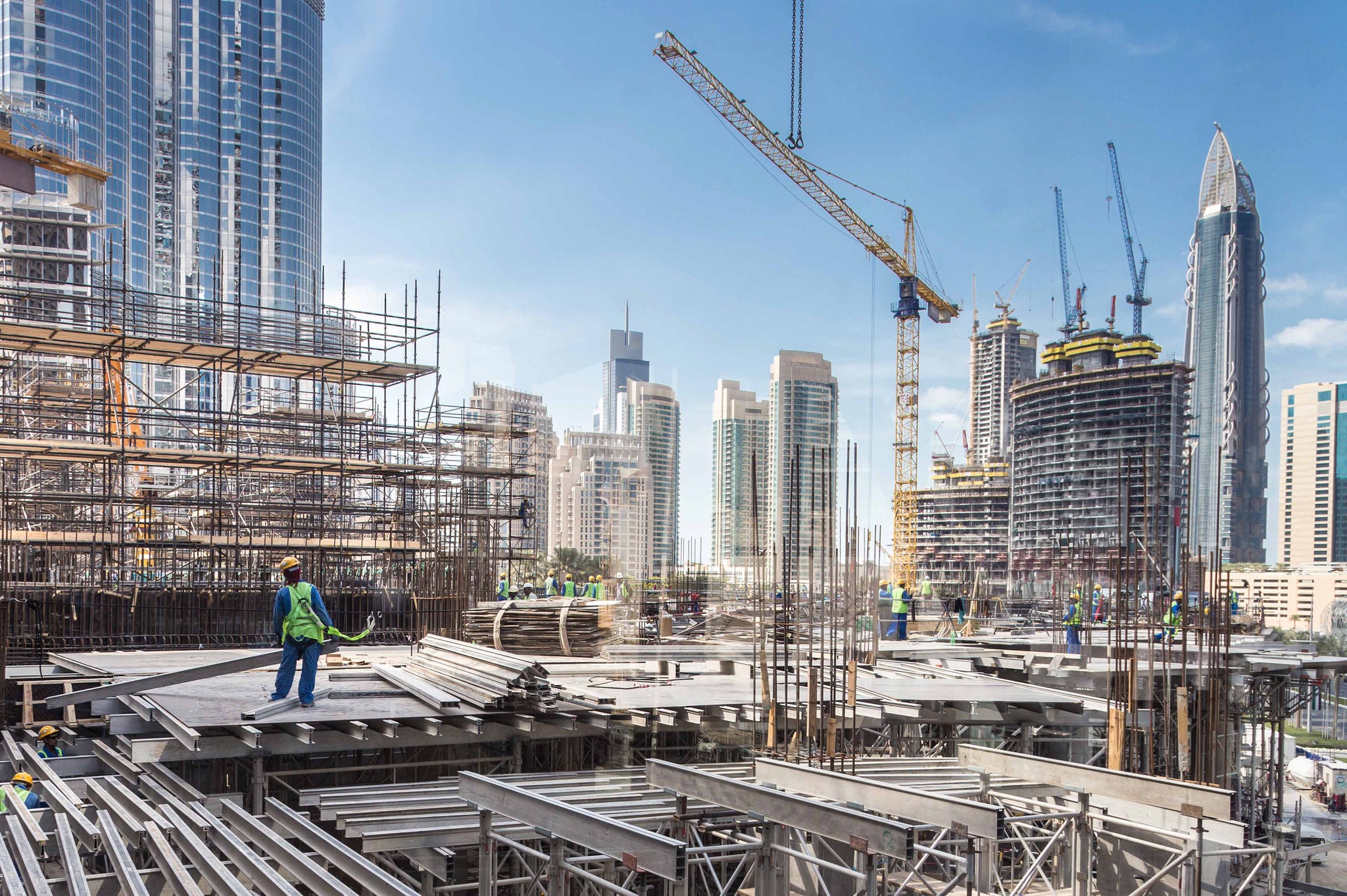 Laborers working on modern constraction site works in Dubai. Fast urban development consept.