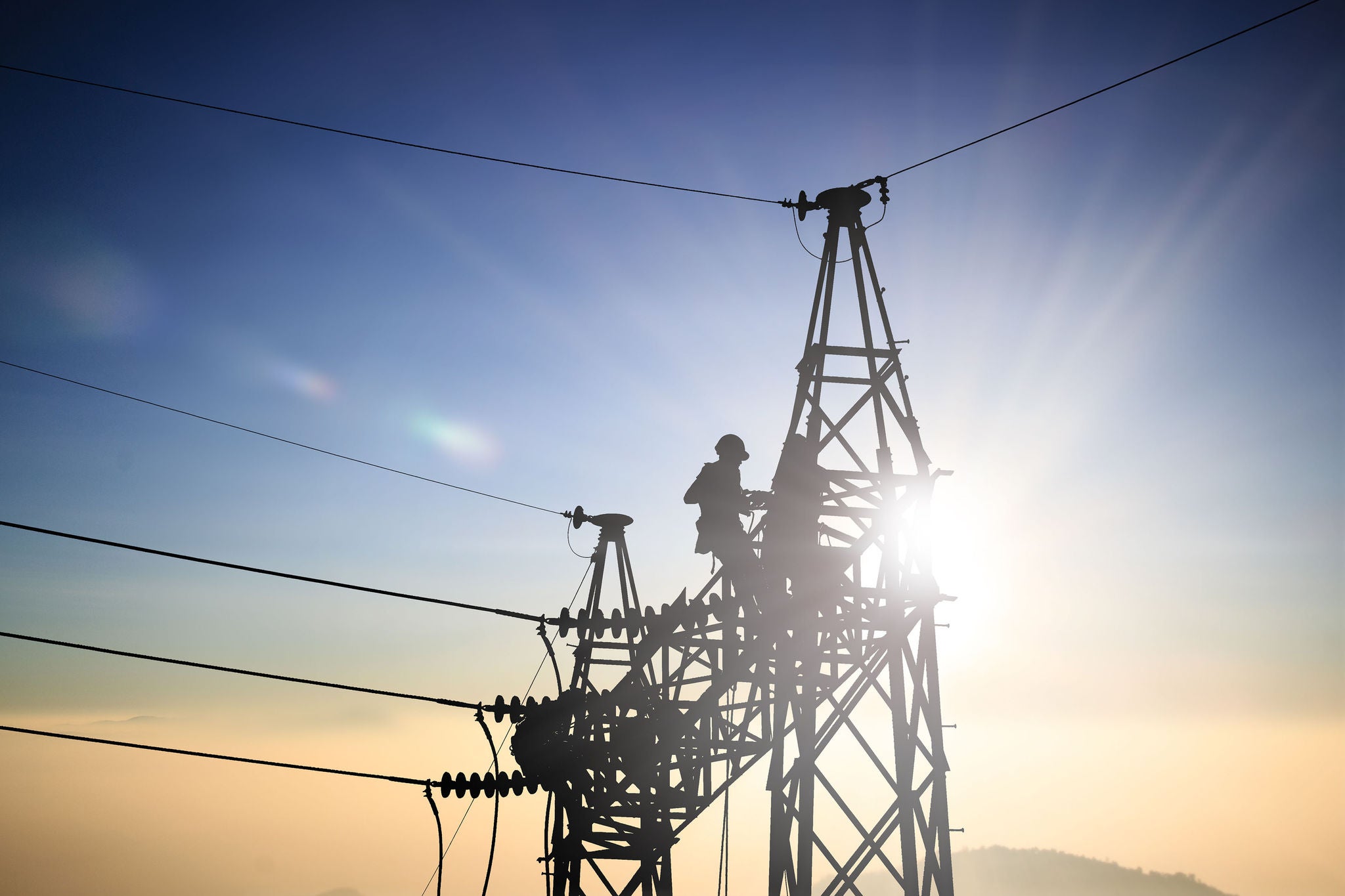 Silhouetteblack man  electrical engineer and electrical workers are installing high voltage systems over blur night city
