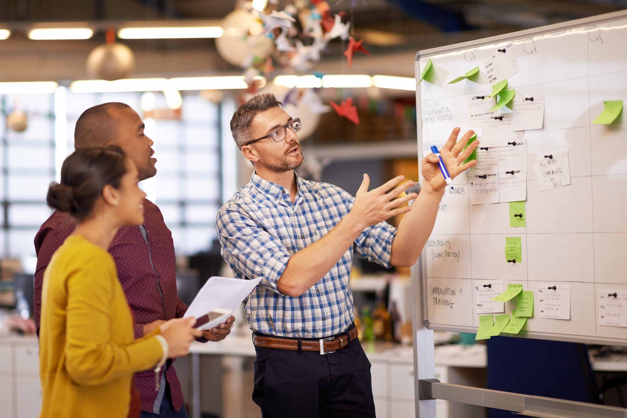 Shot of a group of coworkers brainstorming at a whiteboard.