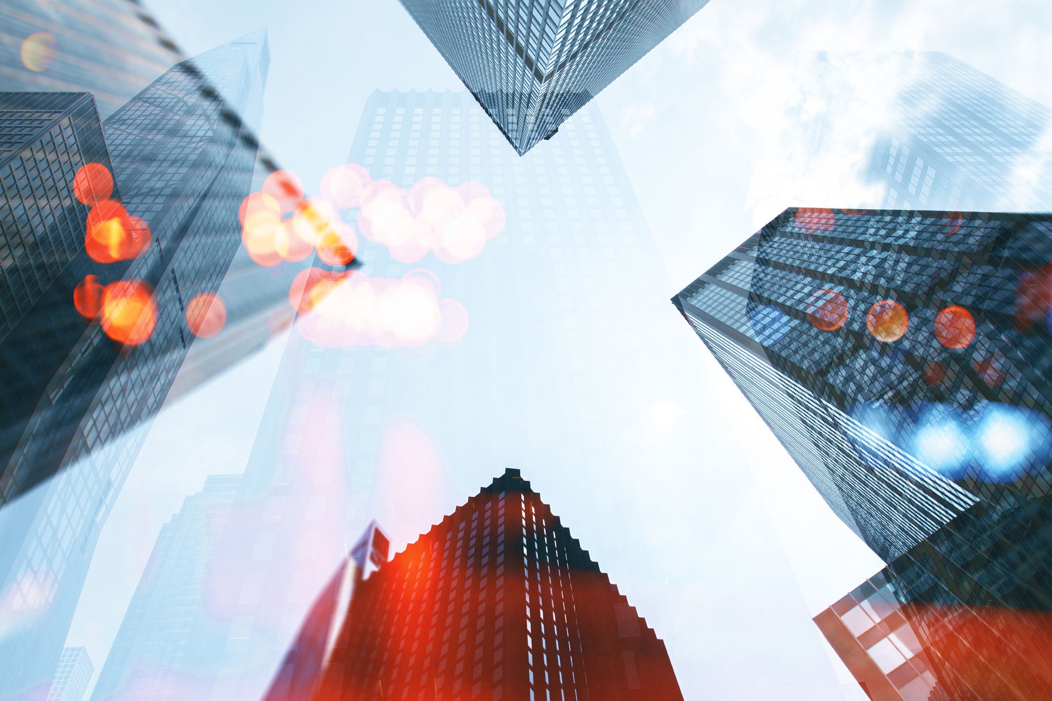Low angle view on tops of modern city office buidings on blue sky background with bokeh