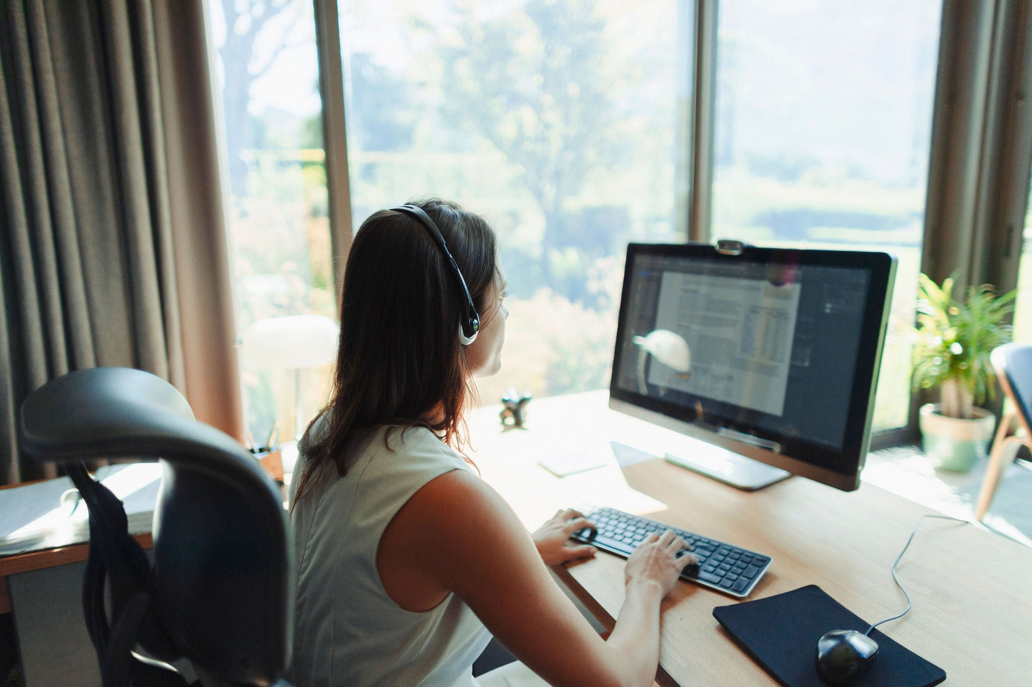 Businesswoman with headset working at computer in home office