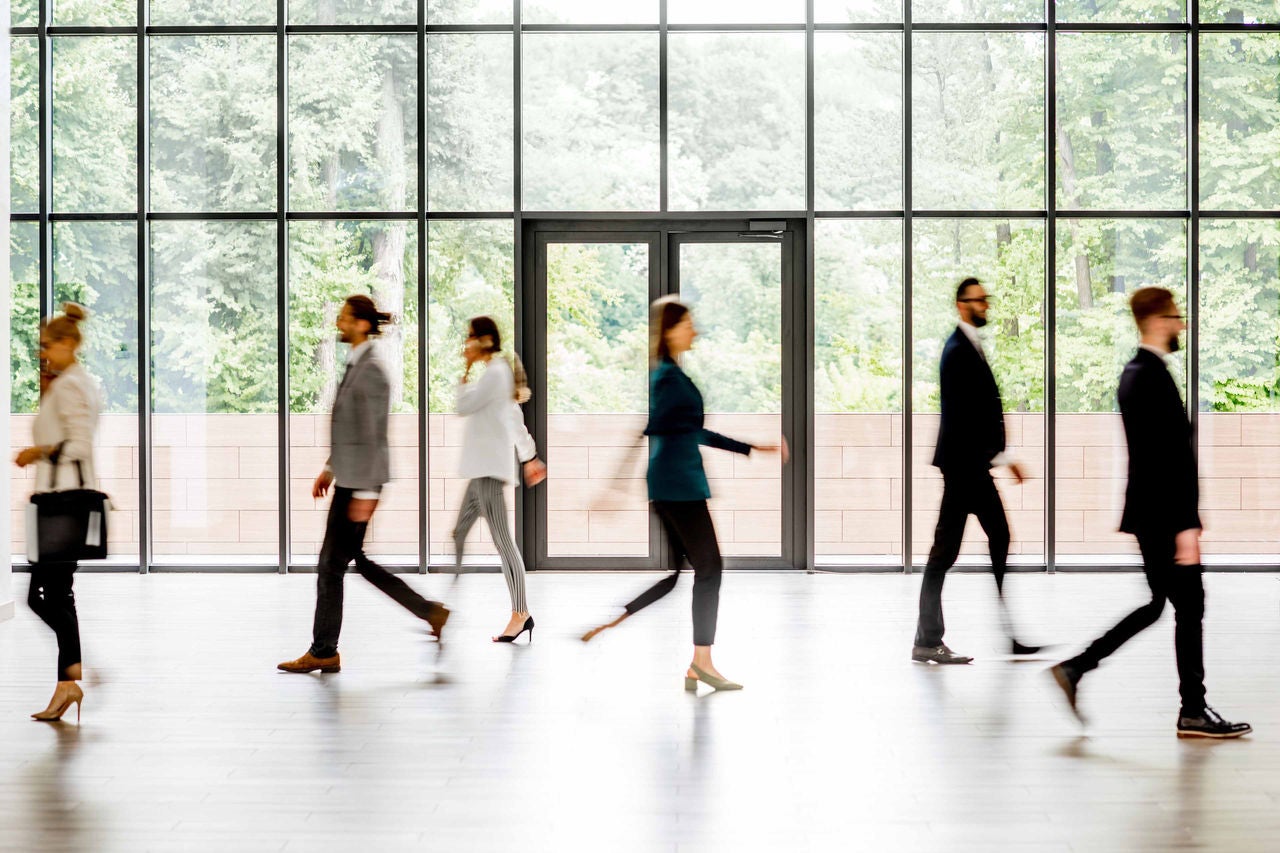 Business people walking at the modern hall on the window background indoors