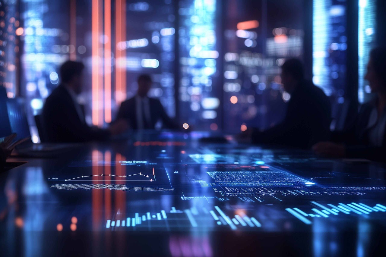 Business people sitting at a table with a computer screen.