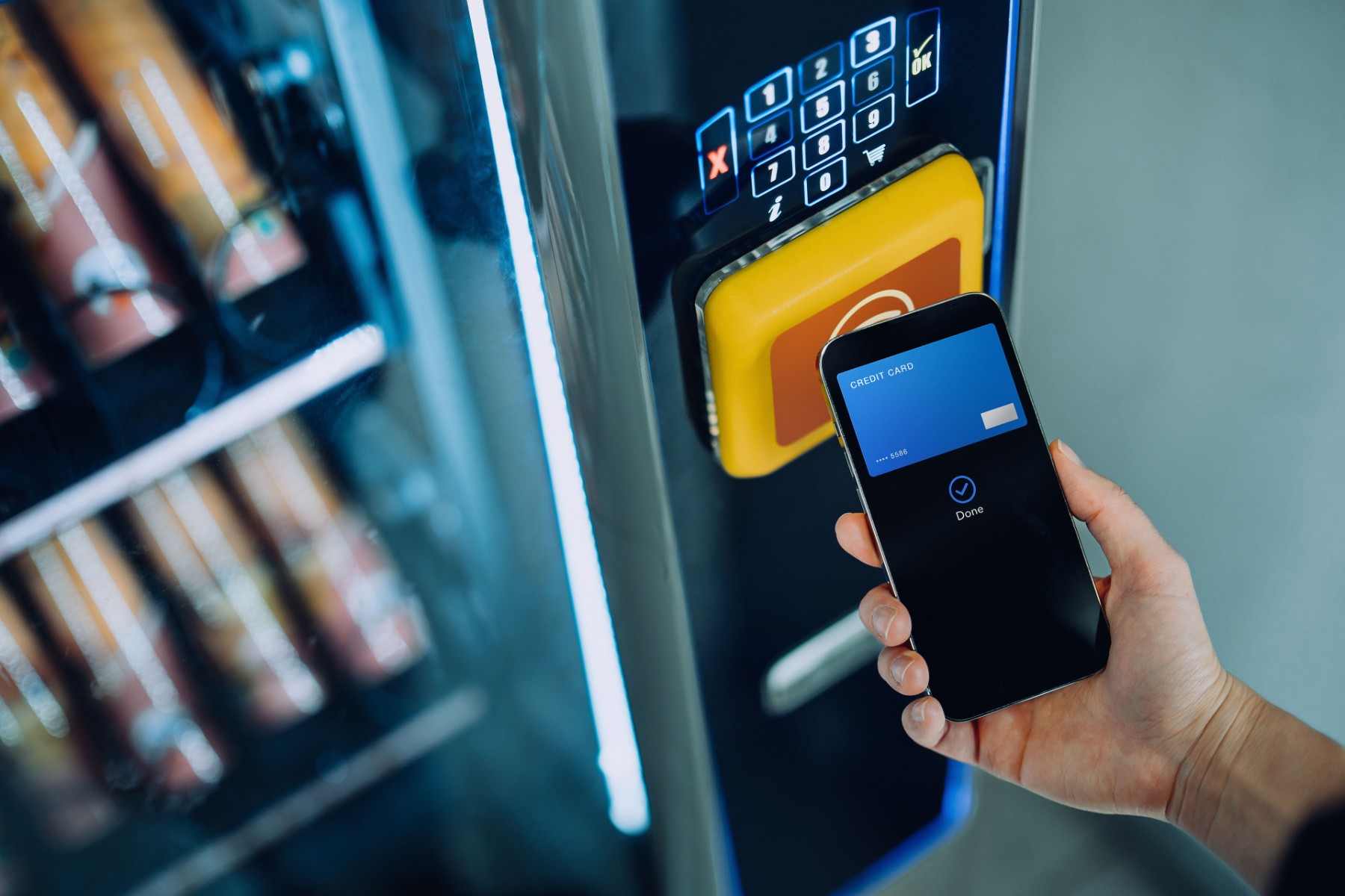Person bezahlt mit Handy an Snackautomat